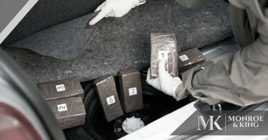 person with gloves on finding blocks of drugs in a car