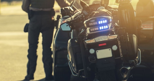 cop on motorcycle approaching driver's side door of a car pulled over