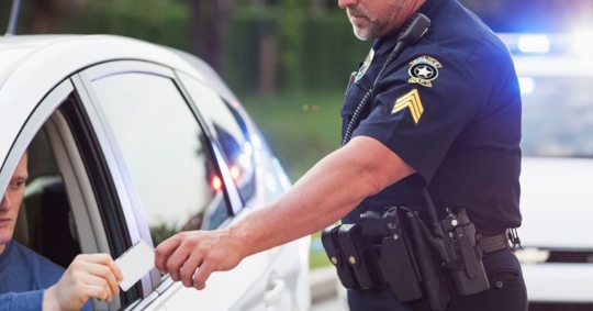 driver handing police officer his ID during a traffic stop