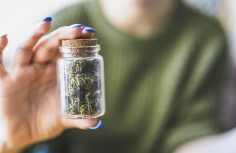woman holding jar of marijuana