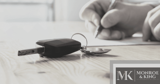 person filling out form with keys on table