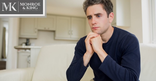 man sitting at home thinking, looking concerned